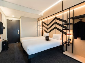 Ein Hotelzimmer mit Bett, Schreibtisch mit Telefon, Fernseher und Kleiderschrank.