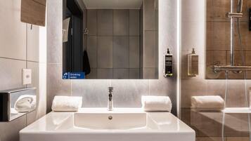 Une salle de bain moderne avec un grand lavabo, un miroir, une douche et un porte-serviettes.