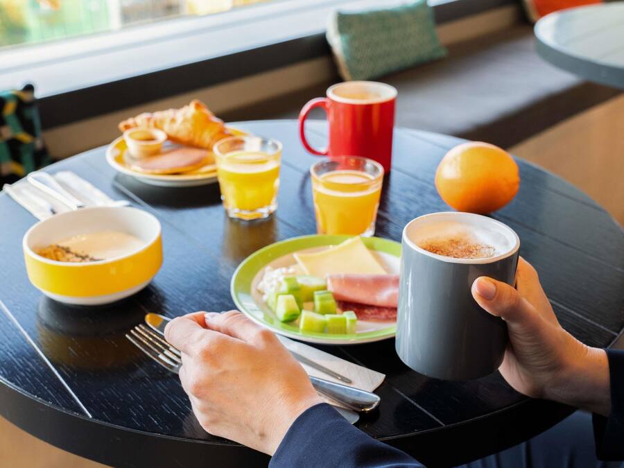Una escena de desayuno con un plato de comida, una taza, un vaso de jugo de naranja y un tazón.