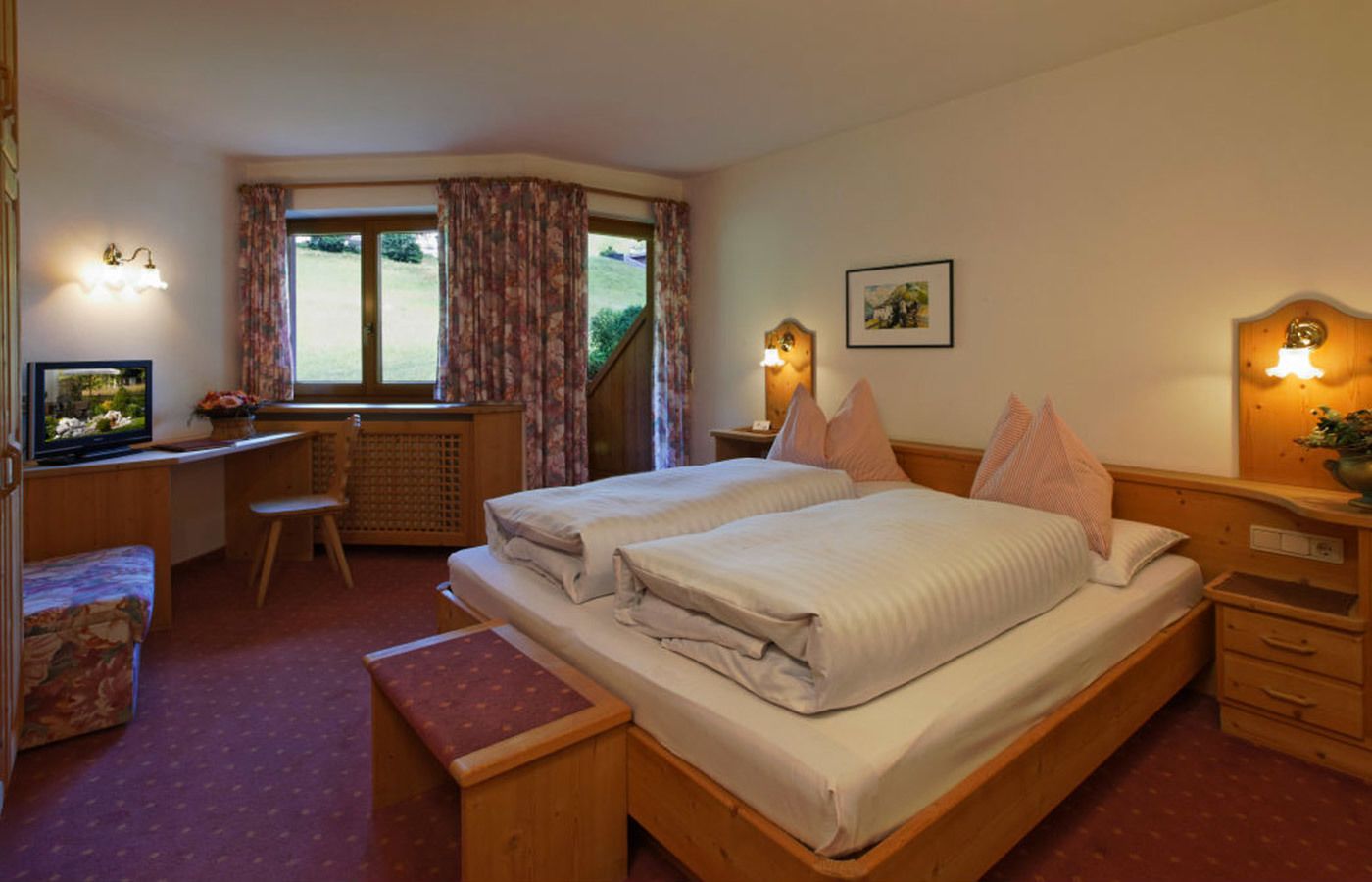 A bedroom with two beds, a desk, a chair, and a television.