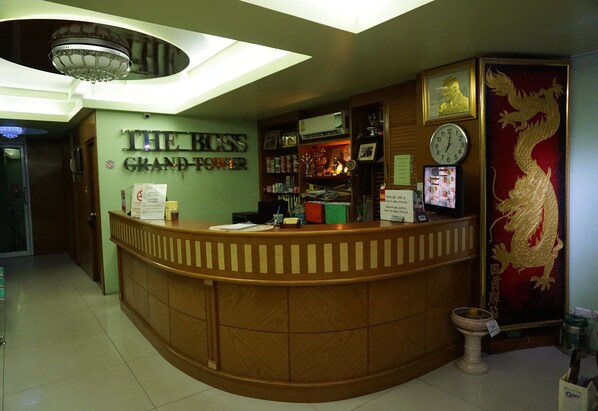A reception desk with a sign reading "THE BOSS GRAND-POWER" in a hotel lobby.