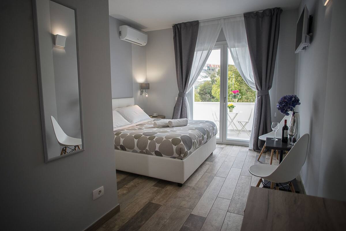 Une chambre moderne avec un lit, un bureau et un balcon offrant une vue agréable.