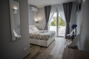 A modern bedroom with a bed, a desk, and a balcony with a view.