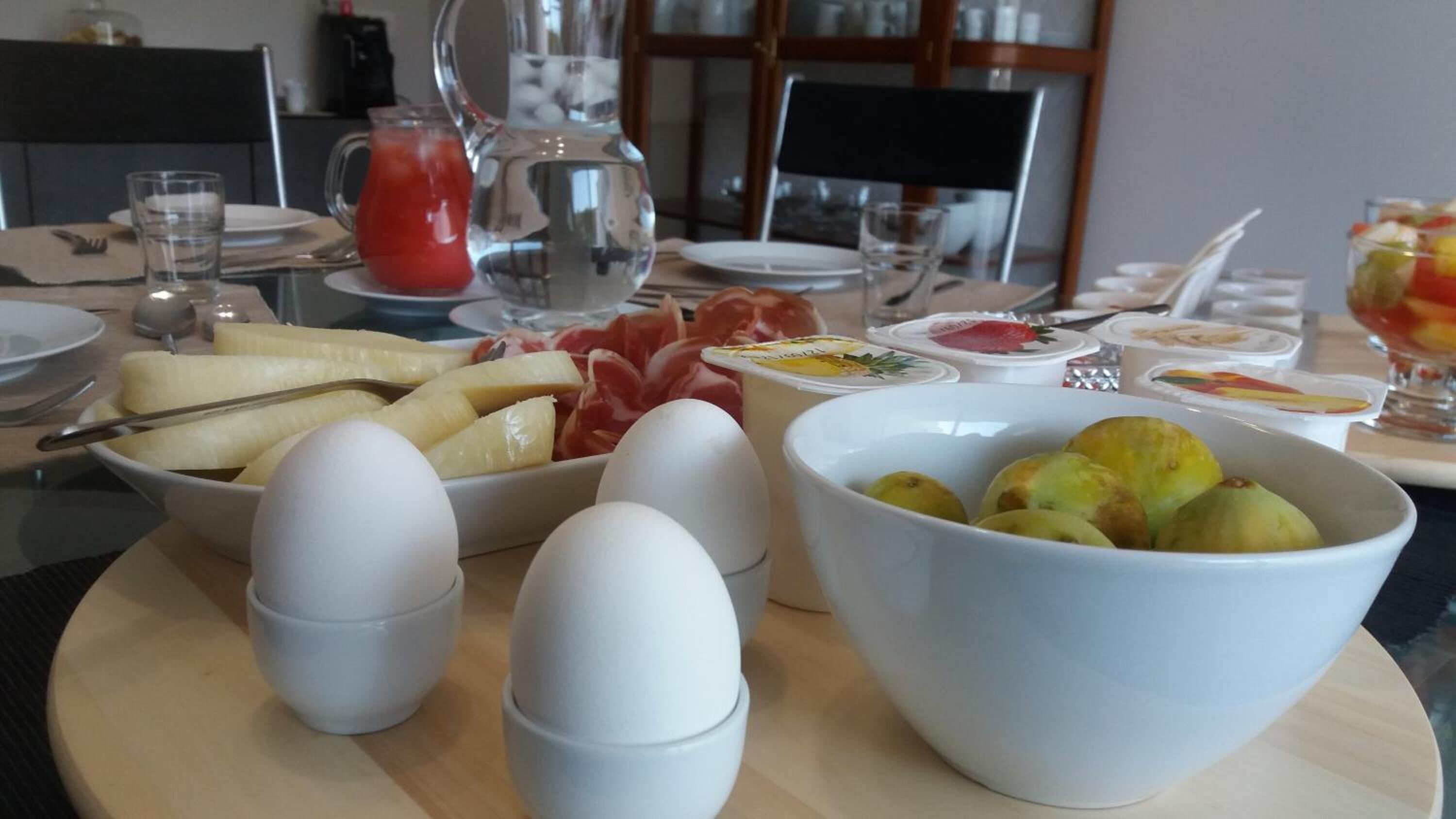 A breakfast setting with eggs, fruits, and various condiments on a table.