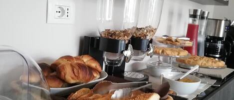 A breakfast buffet with various pastries, bread, and beverages.