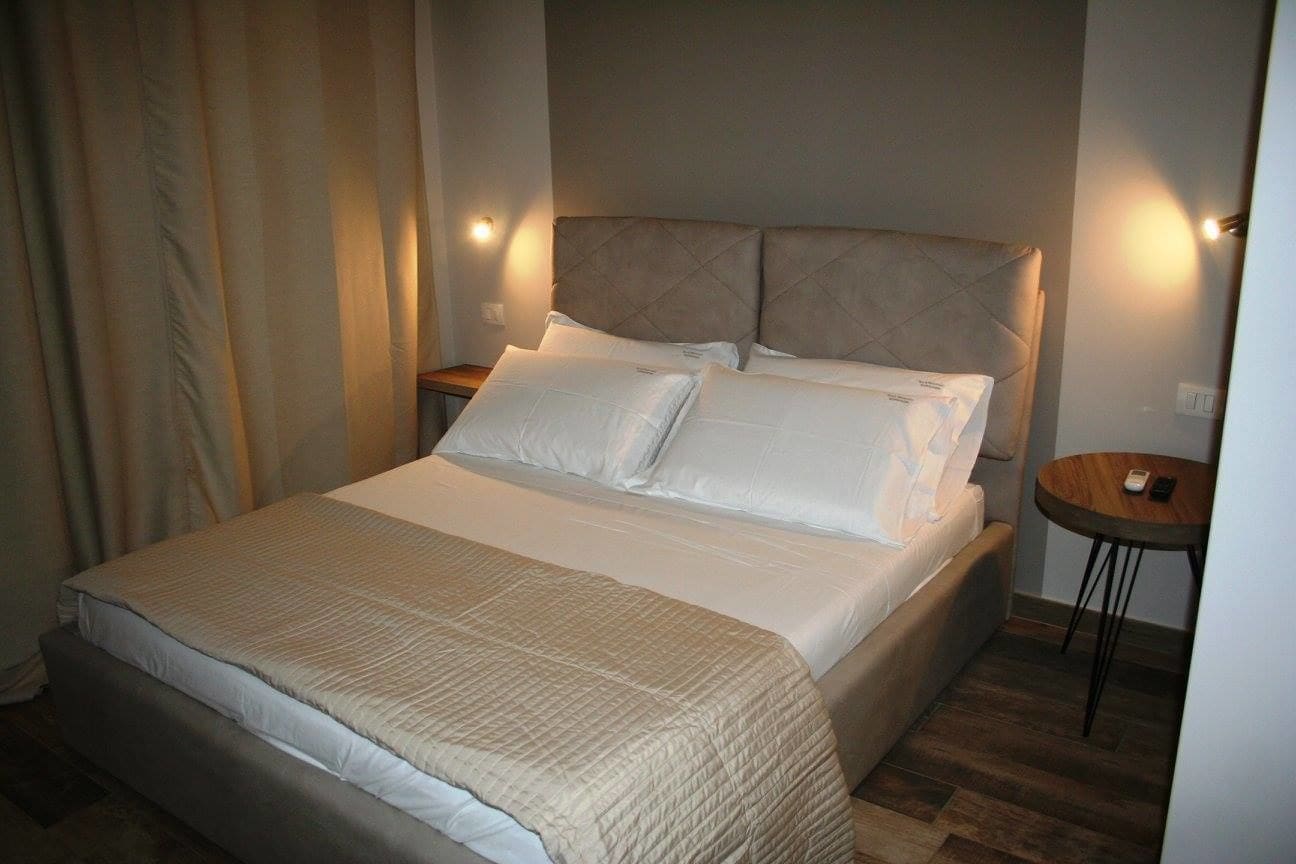 A neatly made bed with a quilted cover, a headboard with a tufted design, and bedside lamps.