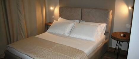 A neatly made bed with a quilted cover, a headboard with a tufted design, and bedside lamps.
