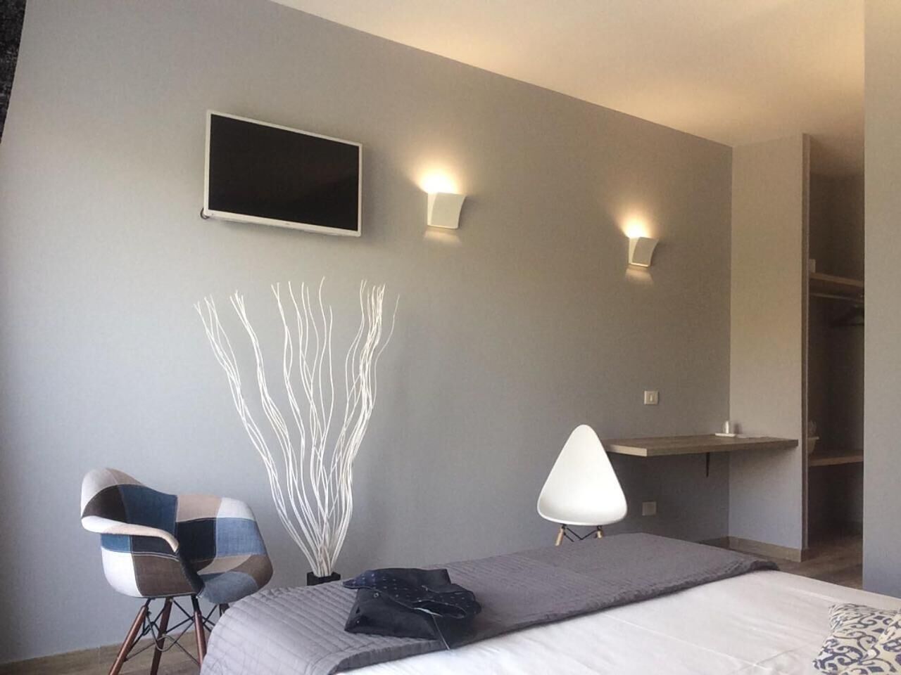 Une chambre d’hôtel moderne équipée d’un lit, d’une chaise, d’un bureau et d’un téléviseur fixé au mur.