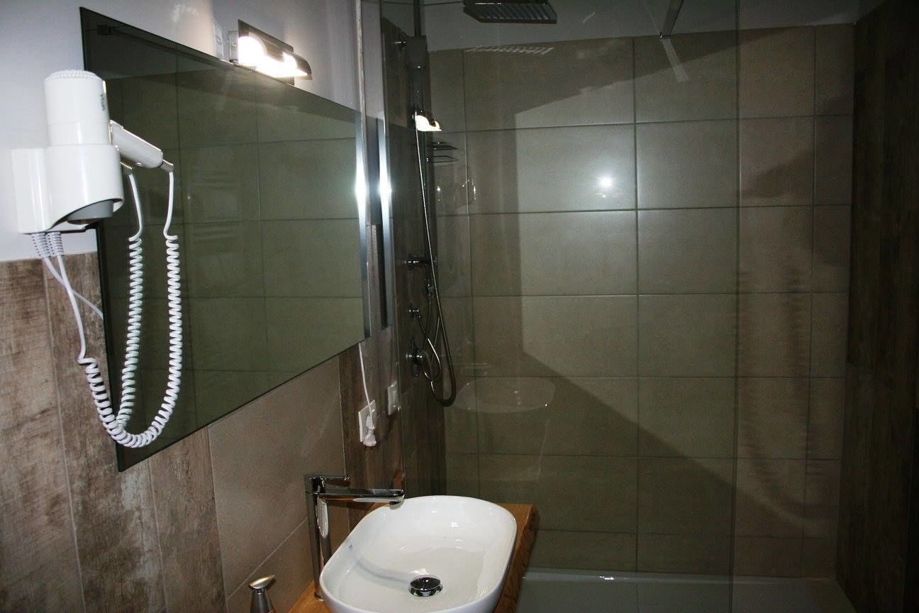 Un baño con lavabo, espejo y ducha.