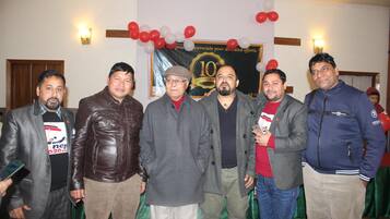 Un grupo de personas de pie en una habitación con un cartel que indica una celebración por el décimo aniversario.