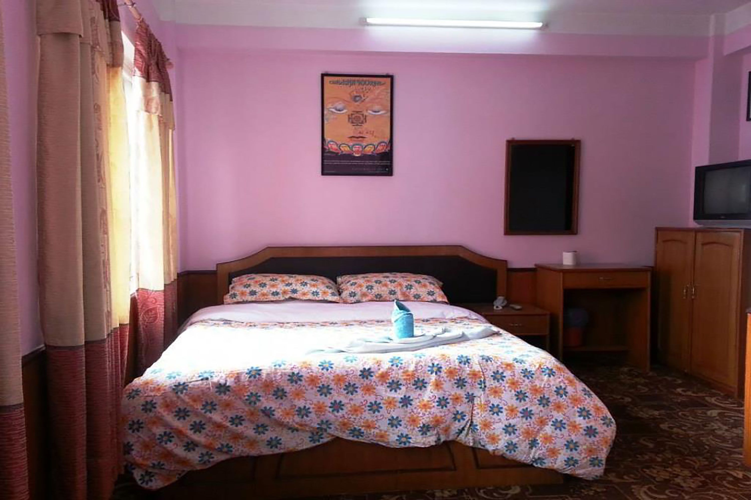 Una camera d'albergo con un letto, una televisione, una scrivania e un armadio.