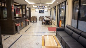 A hotel lobby with a reception desk, seating area, and a large TV screen. - Mirage Inn (Lumbini)