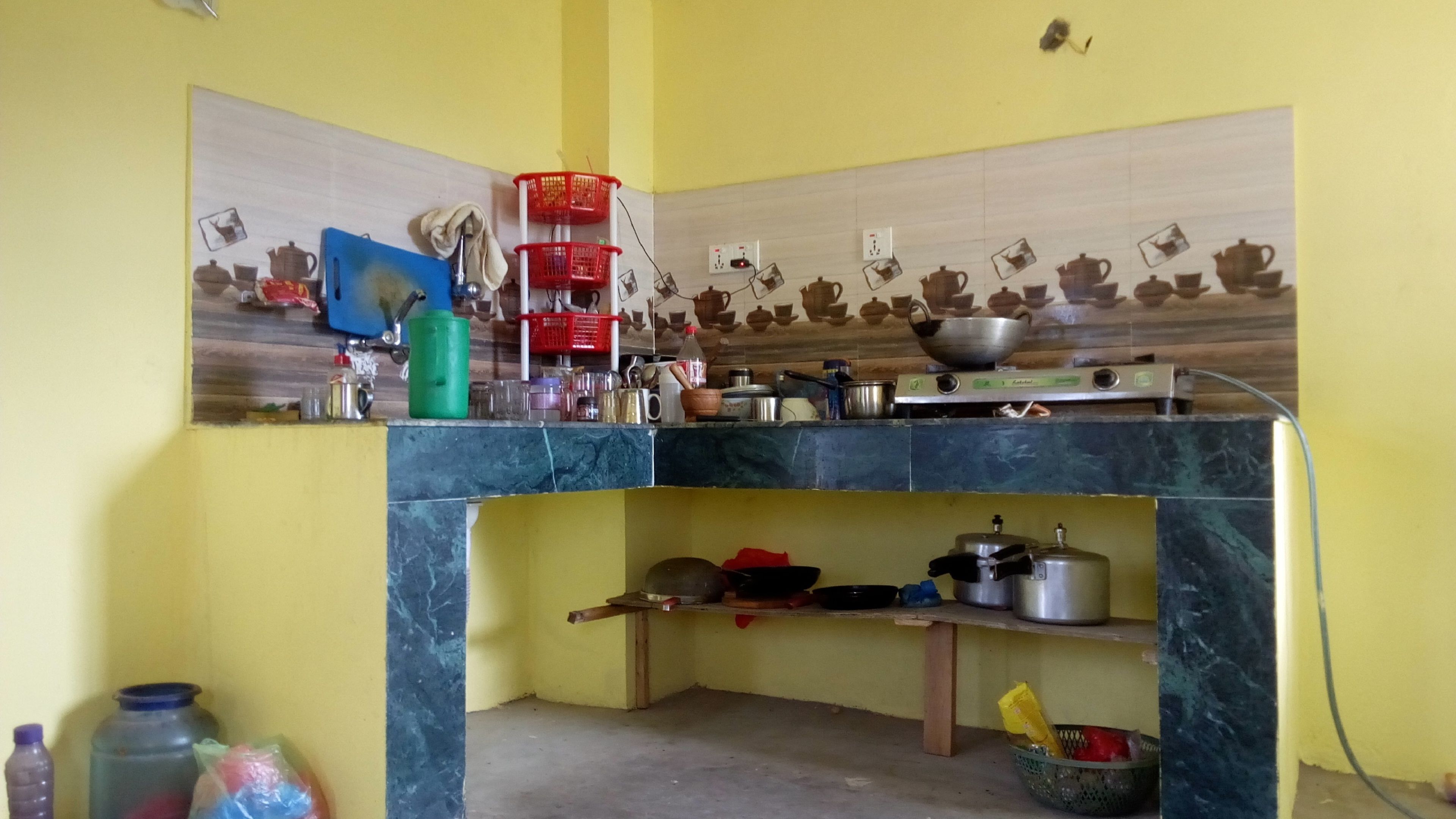 Une cuisine avec un mur jaune, un pare-feu en carrelage et divers ustensiles de cuisine disposés sur des étagères et des plans de travail.