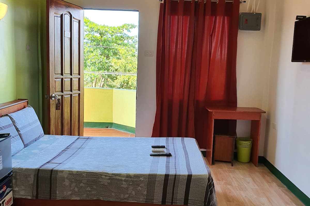 A room with a bed, a desk, and a window with red curtains.