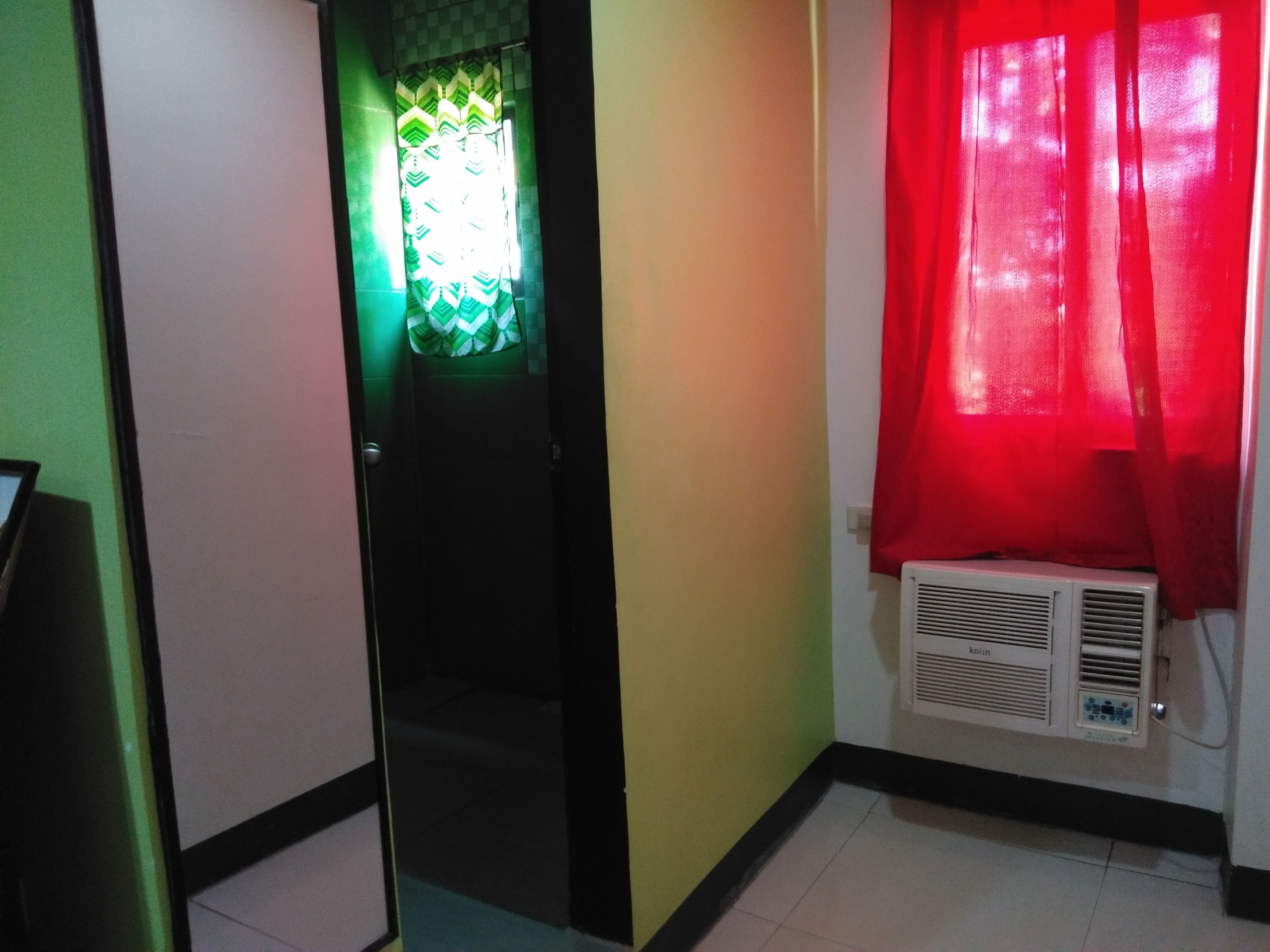A hallway with a door leading to a room, a red curtain, and a wall-mounted air conditioner.