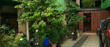 A covered outdoor area with potted plants, a scooter, and a car parked.