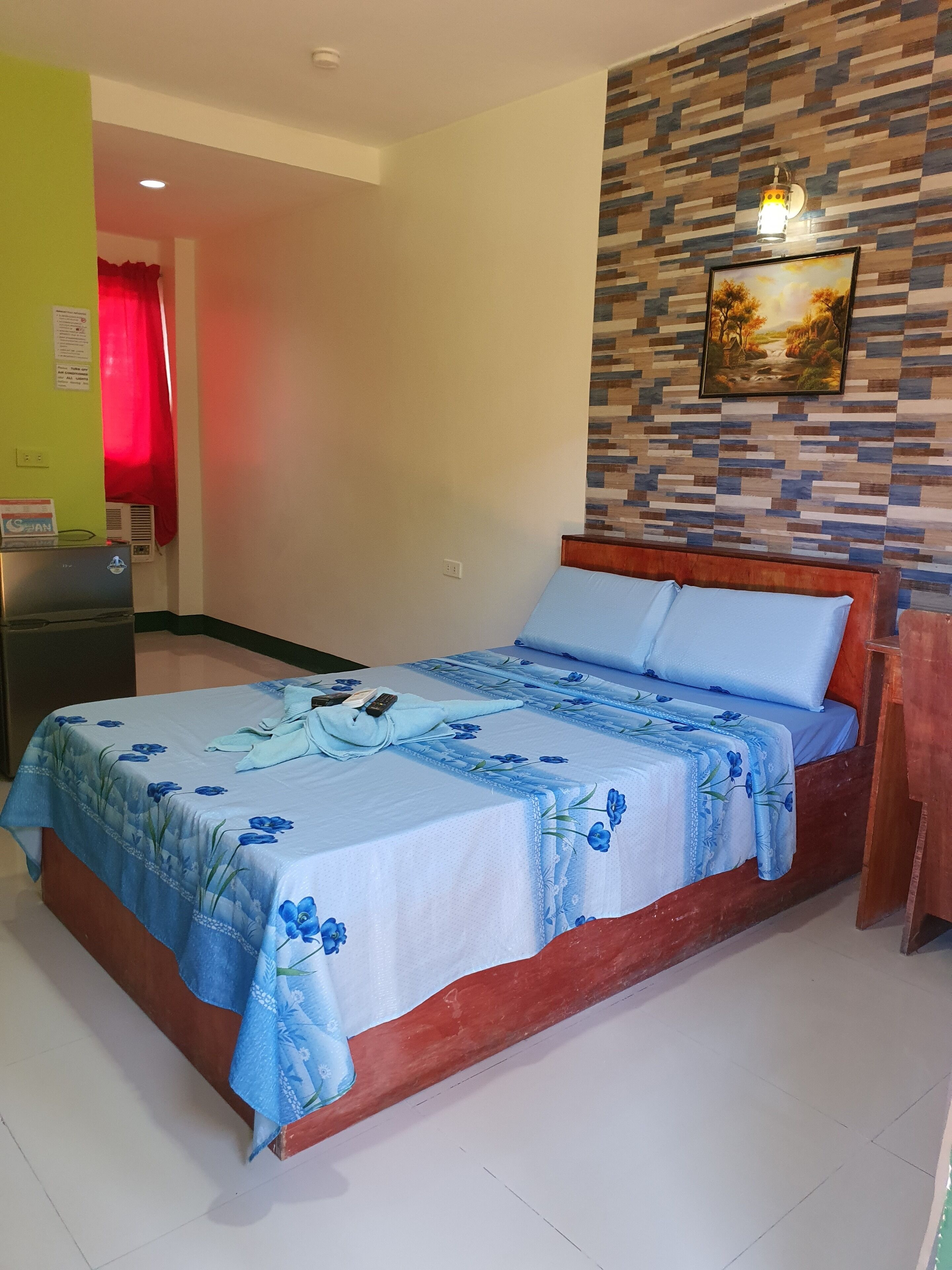 A neatly made bed with a floral bedspread, a wooden headboard, and a wall-mounted picture.