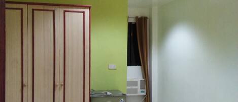 Una stanza con un letto, un armadio, condizionatore d'aria e una tenda.