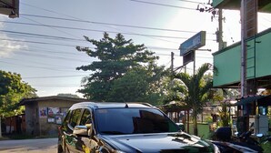 Ein schwarzer SUV steht auf einem Parkplatz, im Hintergrund ist ein Gebäude mit der Aufschrift 'Hotel' zu sehen.
