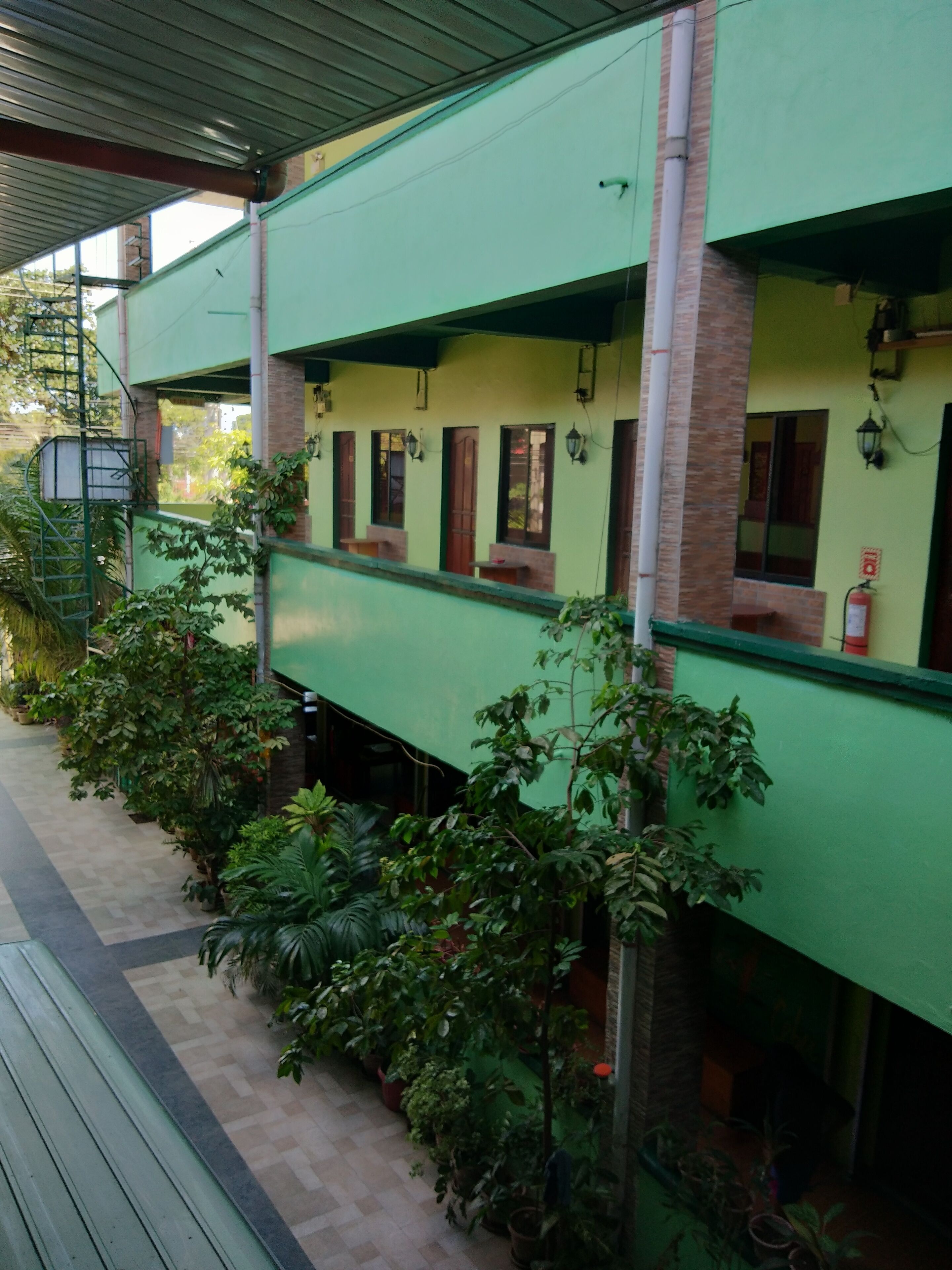 A building with a green facade, multiple windows, and a staircase leading to an upper level.