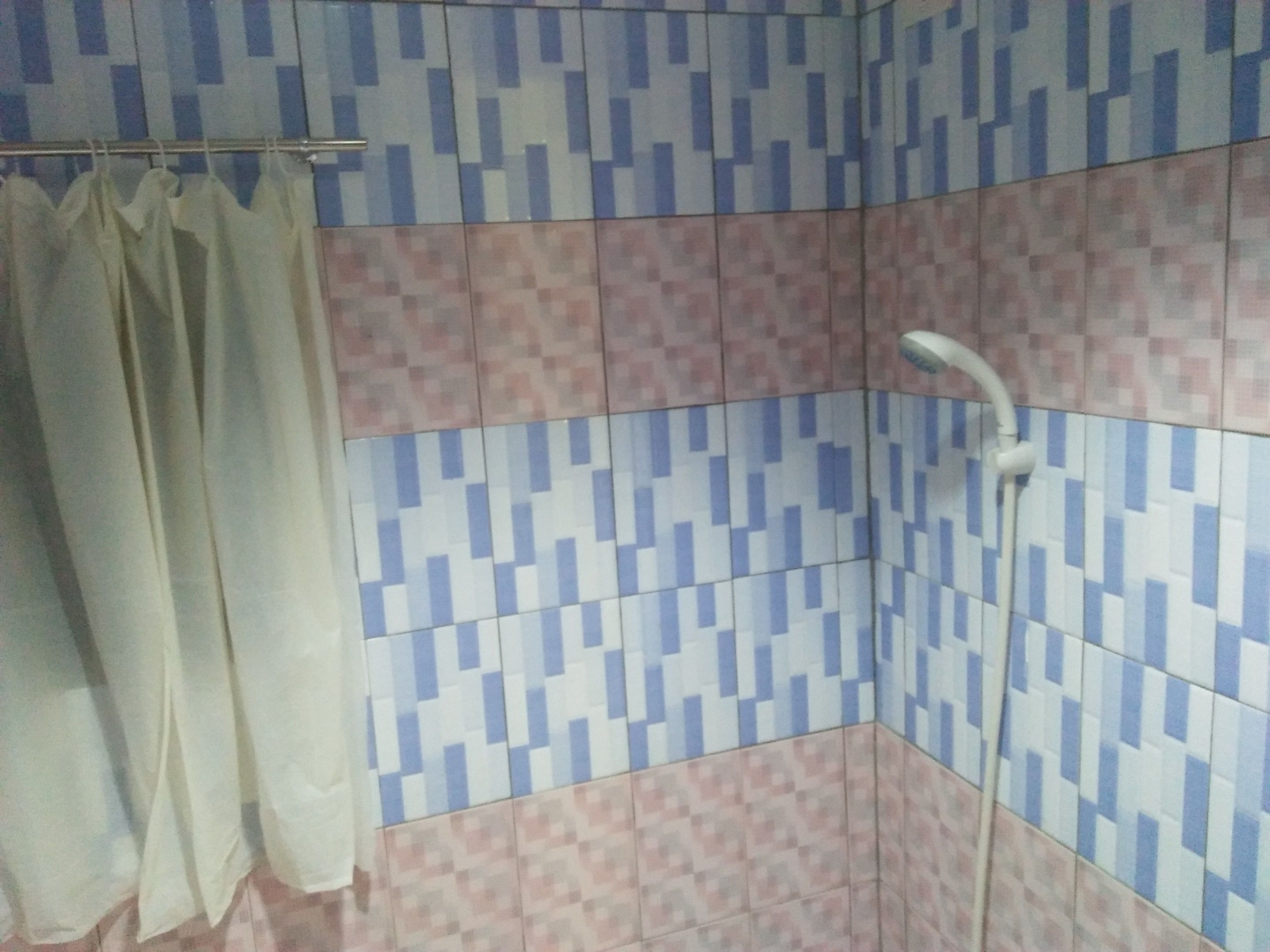 Un baño con baldosas estampadas, una ducha y una cortina.