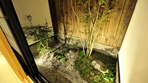 Un pequeño jardín con cerca de madera, suelo de grava y diversas plantas.