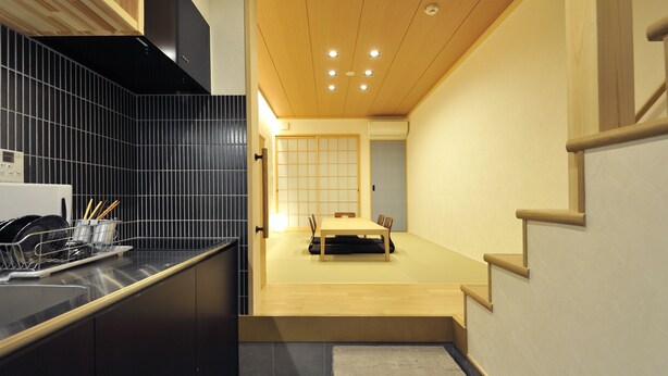 Una cocina moderna con salpicadero de azulejos negros, armarios de madera y lavavajillas integrado.
