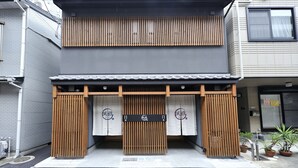 Un edificio japonés tradicional con un portón de madera, puertas correderas y un letrero con caracteres japoneses.