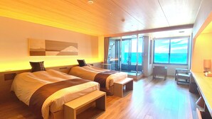 A modern hotel room with two beds, a balcony with a view of the sea, and a small seating area. - Kaisenkaku (Aomori)