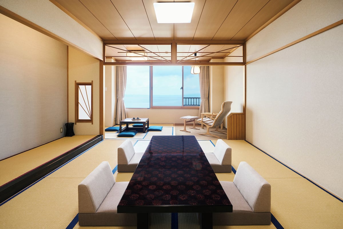 Perinteinen japanilaistyylinen huone, jossa on tatamimatto, matala pöytä ja istuimia.