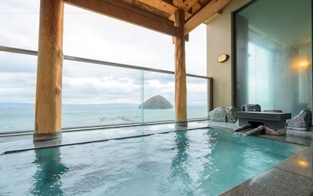 A pool with a view of the sea and a wooden structure.