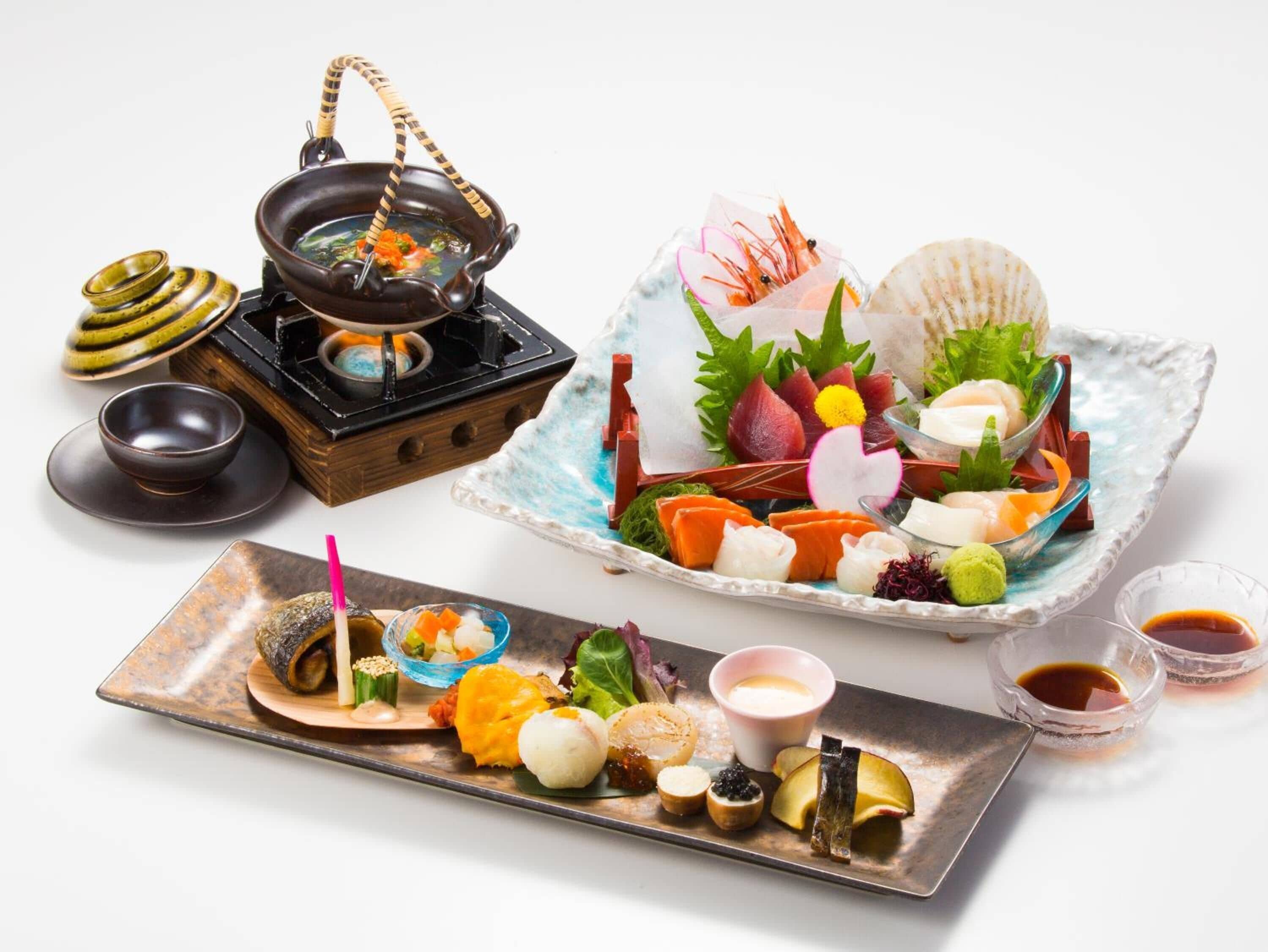 Una presentación tradicional de comida japonesa con un hot pot, sashimi y diferentes acompañamientos.
