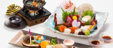 Una presentación tradicional de comida japonesa con un hot pot, sashimi y diferentes acompañamientos.