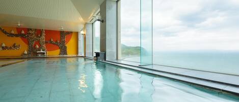 A large indoor swimming pool with a view of the ocean.