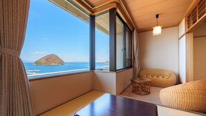 A room with a view of the sea, a wooden table, a sofa, and a small table with chairs. - Kaisenkaku (Aomori)