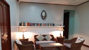 Una sala de estar con muebles de mimbre, una estantería y un reloj de pared.