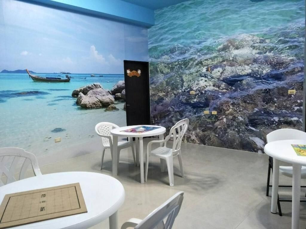 A room with a mural of a beach scene, white chairs, and a table with a menu.