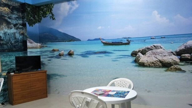 Ein Zimmer mit Wandmalerei einer Strandansicht, einem Holzschrank und einem Tisch mit Stühlen.