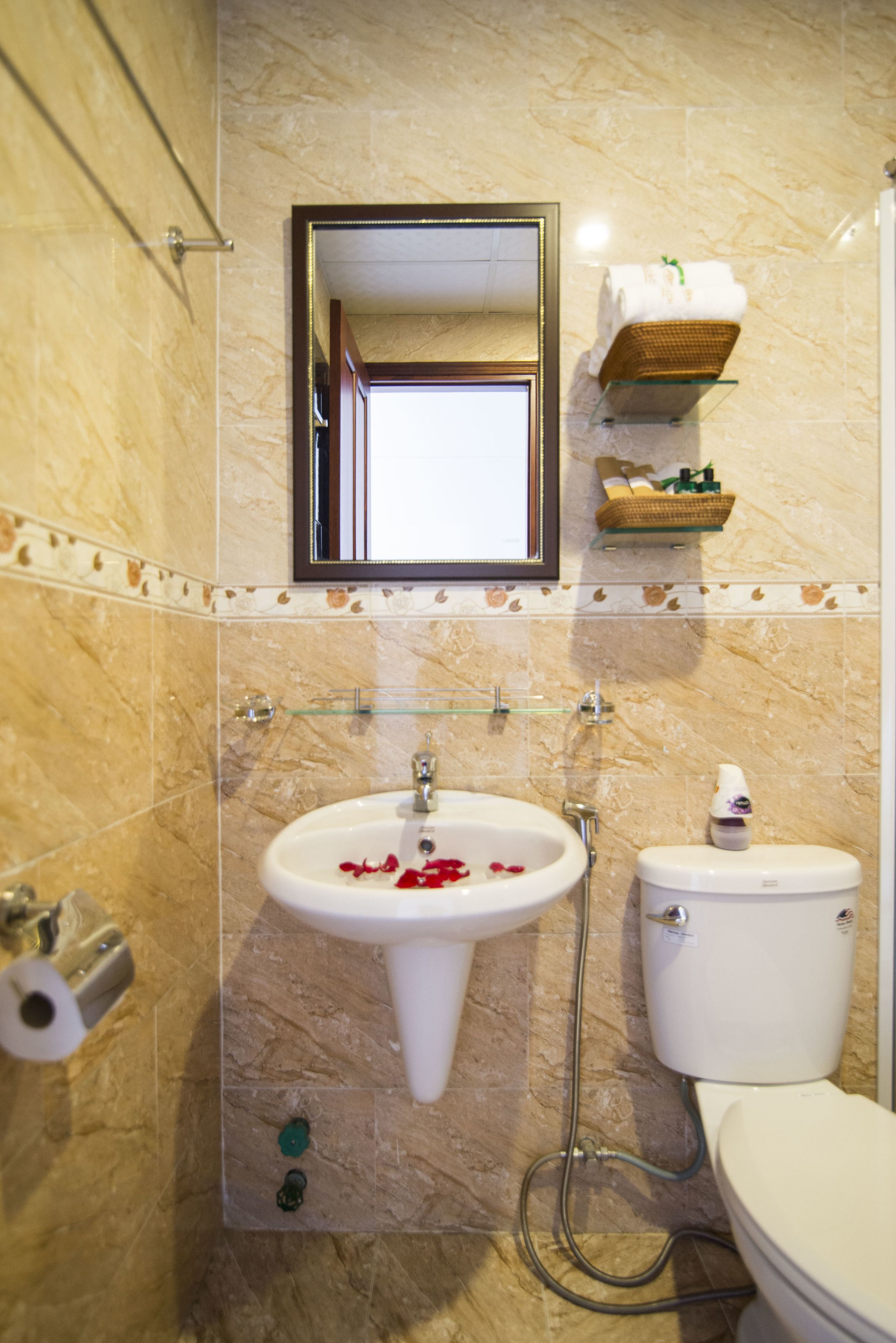 Une salle de bain avec un lavabo en marbre, des toilettes et un miroir au-dessus du lavabo.