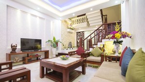 Una sala de estar moderna con televisor, muebles de madera, una escalera y plantas decorativas.