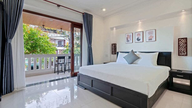Habitación de hotel moderna con una cama grande, un balcón con vistas a zonas verdes y un piso de baldosas impecable.