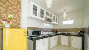 A modern kitchen with white cabinets, a yellow refrigerator, a microwave, and a sink. - Platoo Pool Villa (Hua Hin)