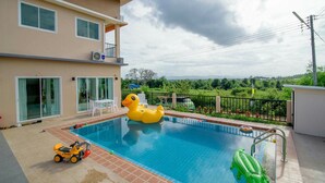 A swimming pool with inflatable toys, a patio area, and a view of the landscape. - Platoo Pool Villa (Hua Hin)