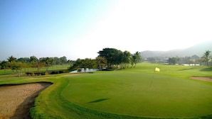 Un campo da golf con un green curato, bunker di sabbia e un’asta di segnalazione.