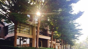 Un edificio moderno con diversi piani, ampie finestre e un balcone al livello superiore.