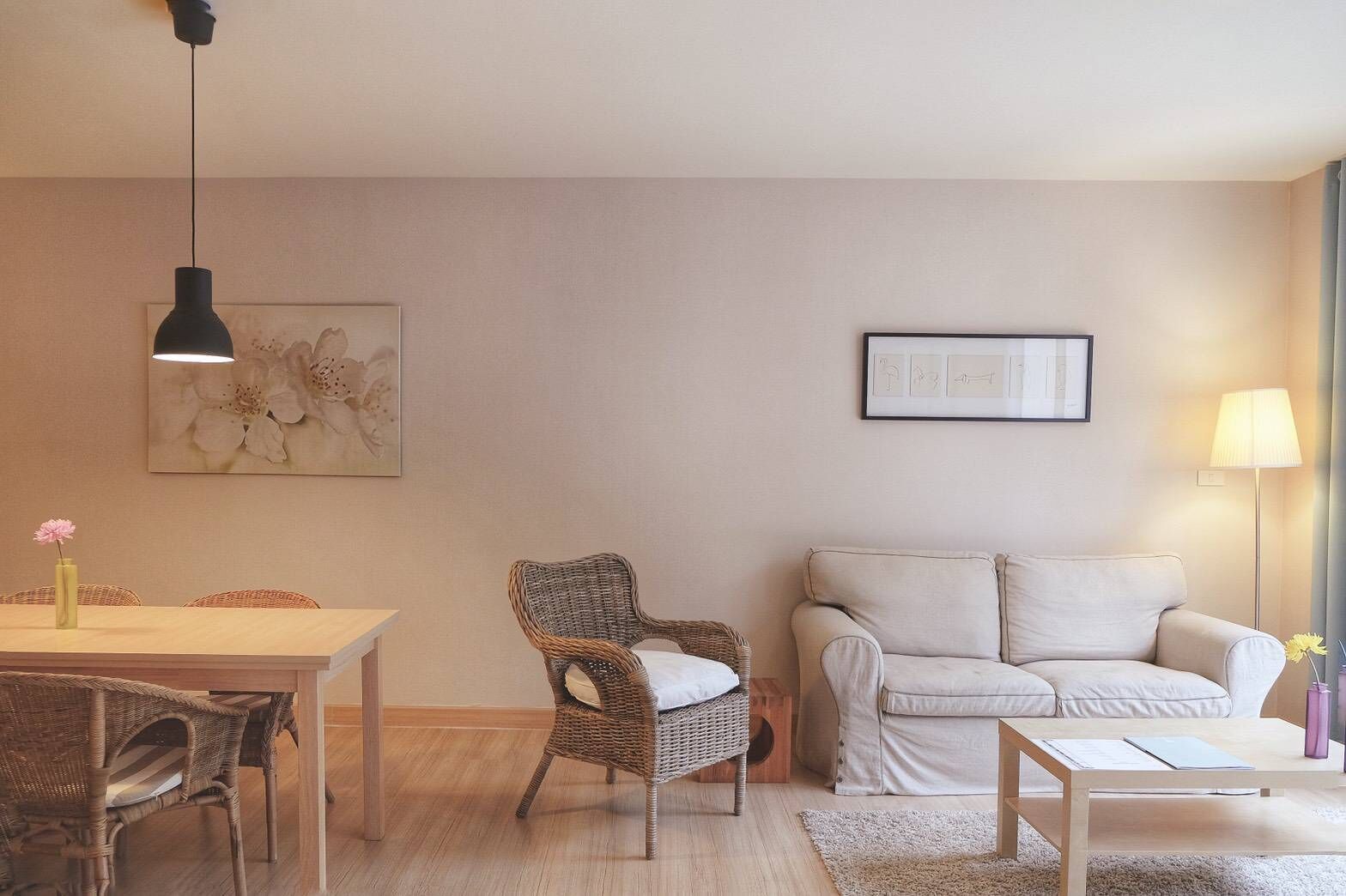 Un salon comprenant une table à manger, des chaises en osier, un canapé, une petite table basse et une lampe.