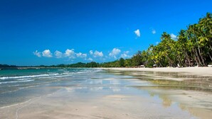 A beach with clear blue water, sandy shore, and palm trees. - Ngapali Paradise Hotel (Thandwe)
