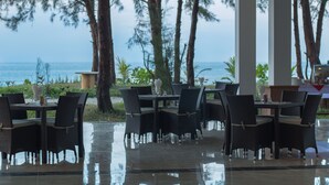 An outdoor dining area with tables and chairs, overlooking a body of water. - Ngapali Paradise Hotel (Thandwe)