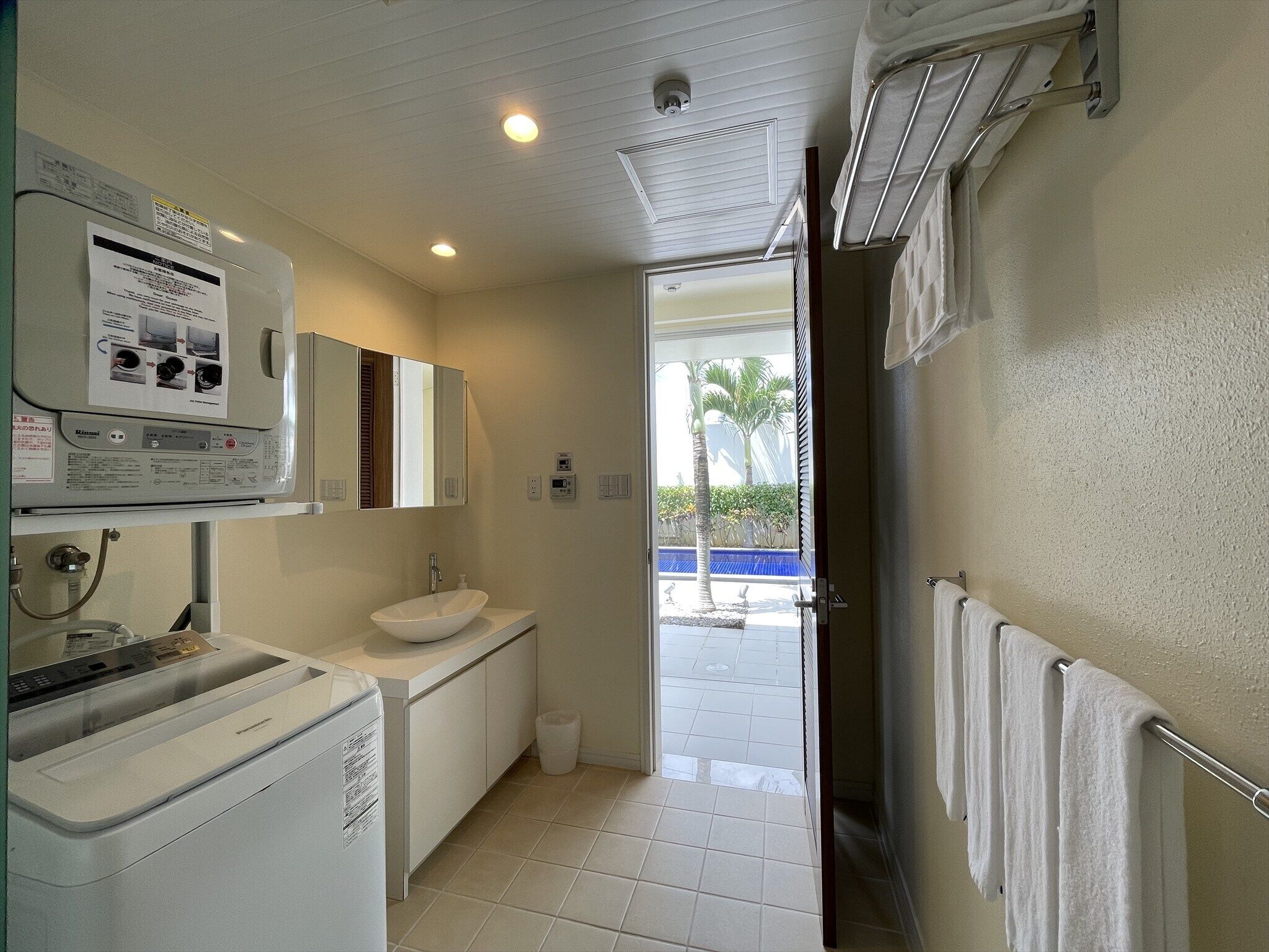 A hotel bathroom with a sink, mirror, and towel rack.
