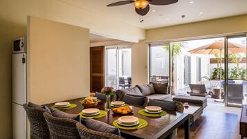 A modern dining area with a wooden table set for four, surrounded by wicker furniture.